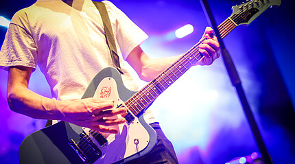 Ausschnitt eines Mannes der Gitarre spielt