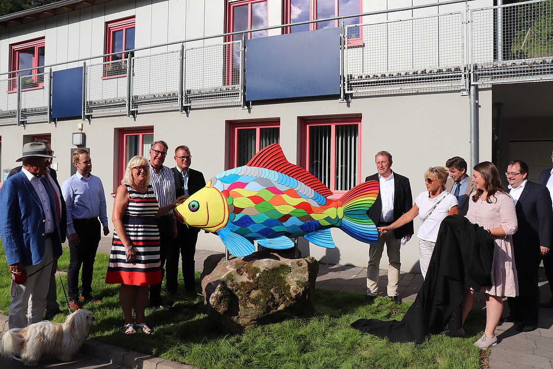 Enthüllung des Phantastischen Karpfens Das Bild zeigt die Enthüllung des Phantastischen Karpfens. Bezirkstagspräsident Henry Schramm bestaunt mit weiteren Personen den Regenbogenfisch.