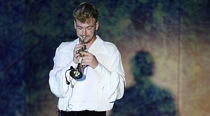 ein junger Mann im weißen Hemd spielt auf einer Trompete