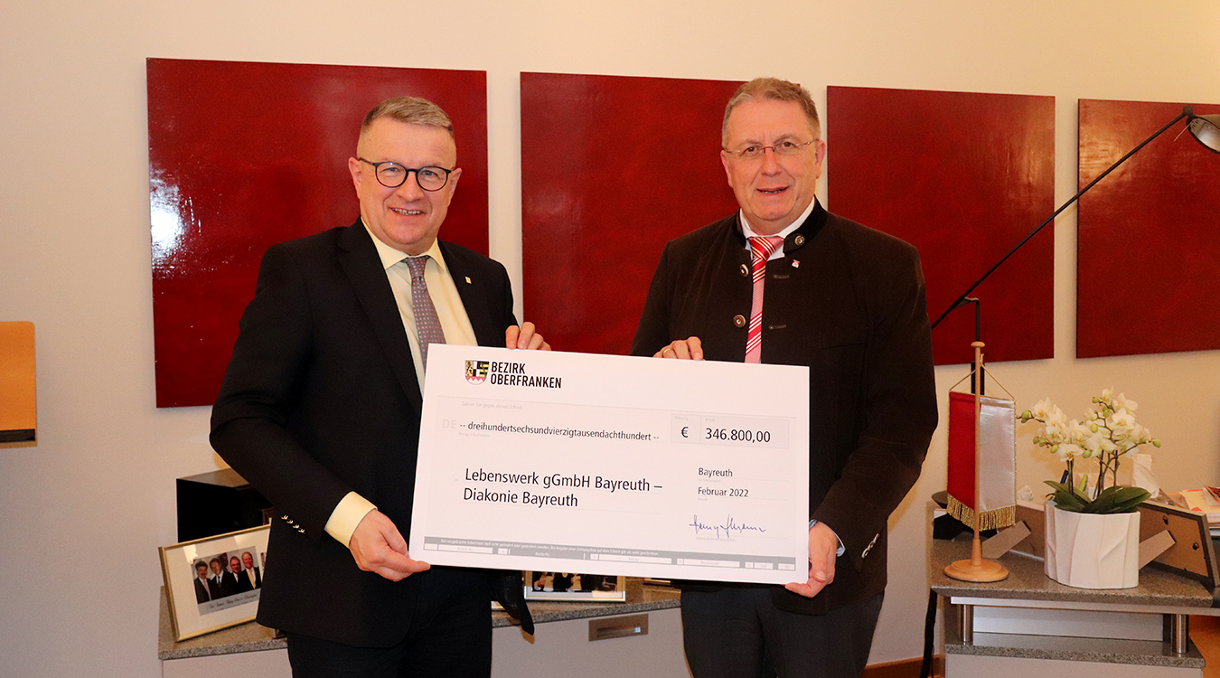 Dr. Franz Sedlak und Henry Schramm Zwei Männer stehen nebeneinander und halten gemeinsam einen Scheck.