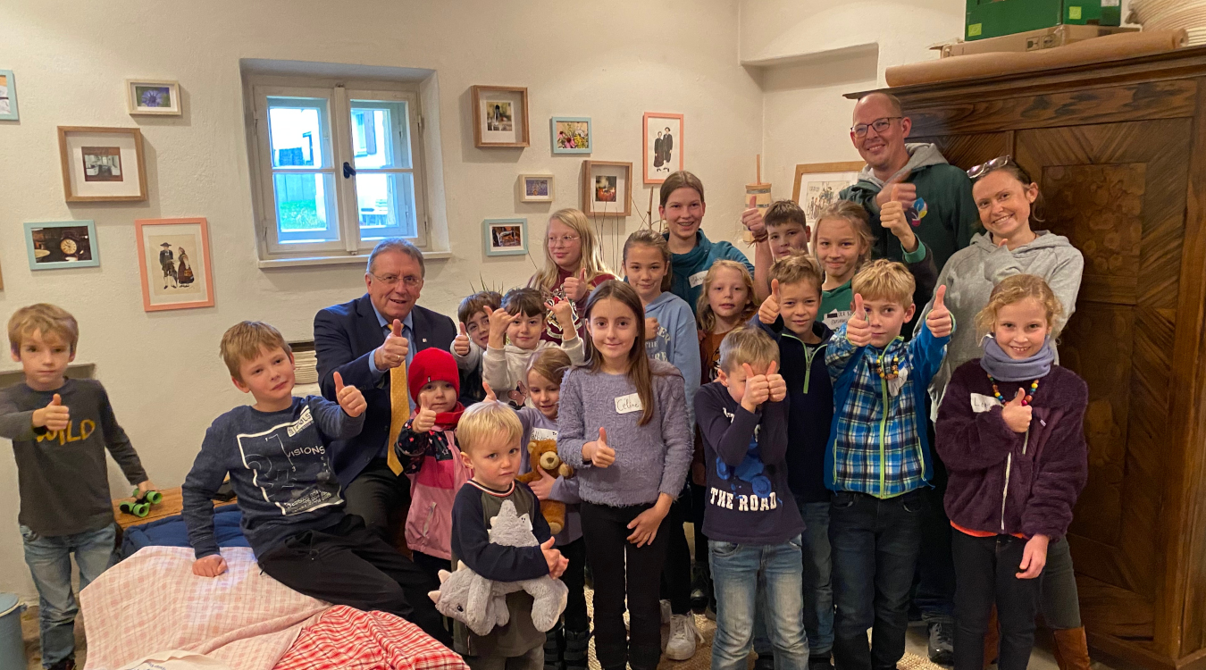 Kinder in der Lernwerkstatt Viele Kinder stehen in einer Gruppe beinander und zeigen den Daumen hoch in die Kamera. Auch zwei Männer und eine Frau sind dabei