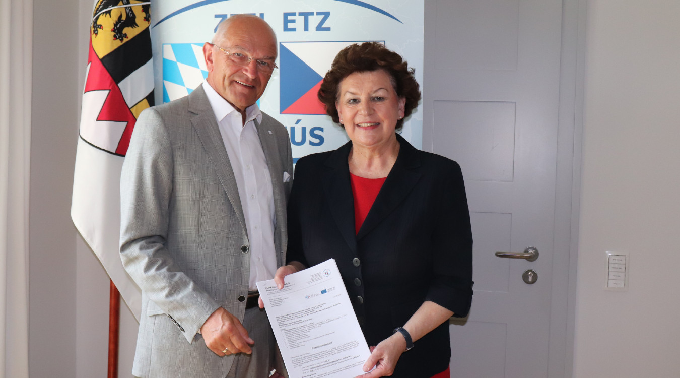 Bezirkstagspräsident Dr. Günther Denzler nimmt den Förderbescheid von Dr. Birgit Seelbinder entgegen.
