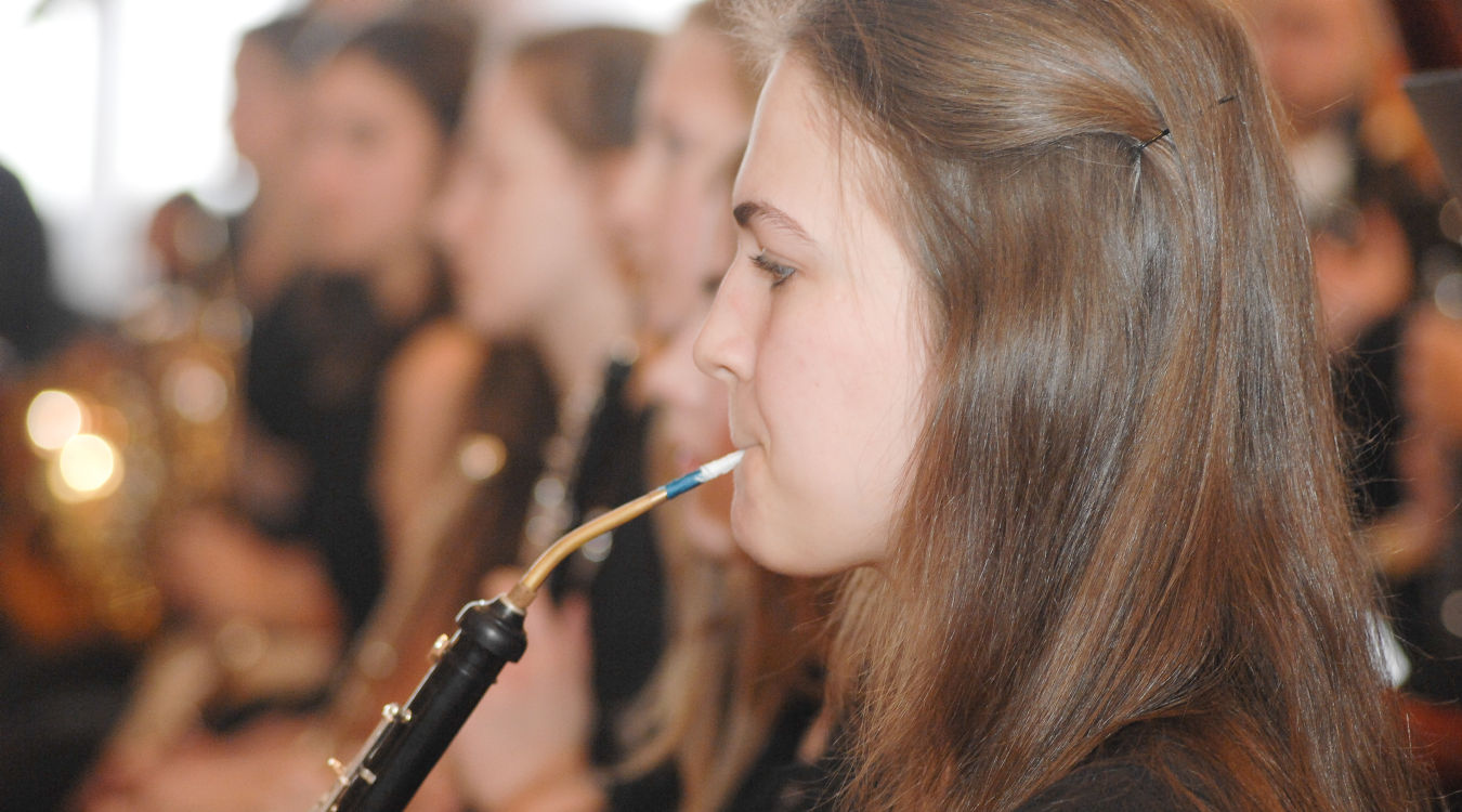 Konzert Oboe Ein Mädchen spielt Oboe - im Hintergrund unscharf weitere Musiker