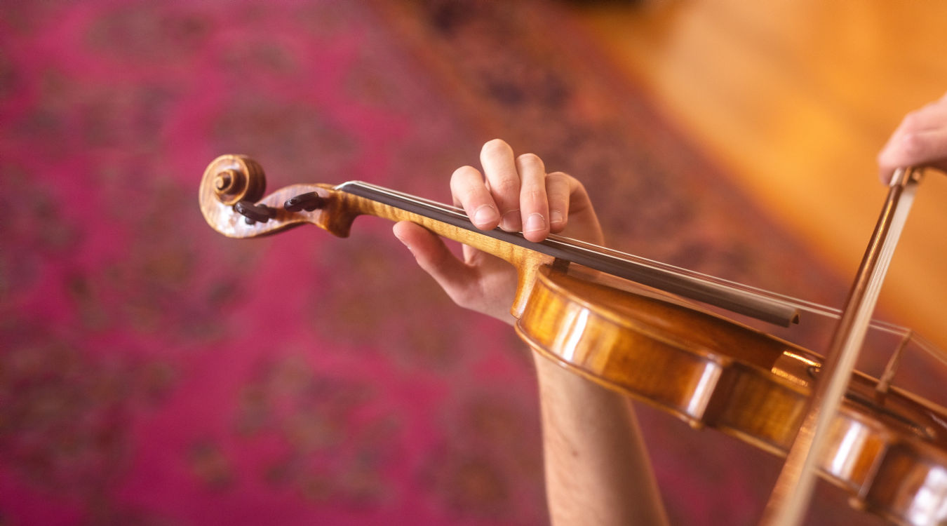 Der Hals und der mittlere Teil einer Violine, gehalten von einer Hand