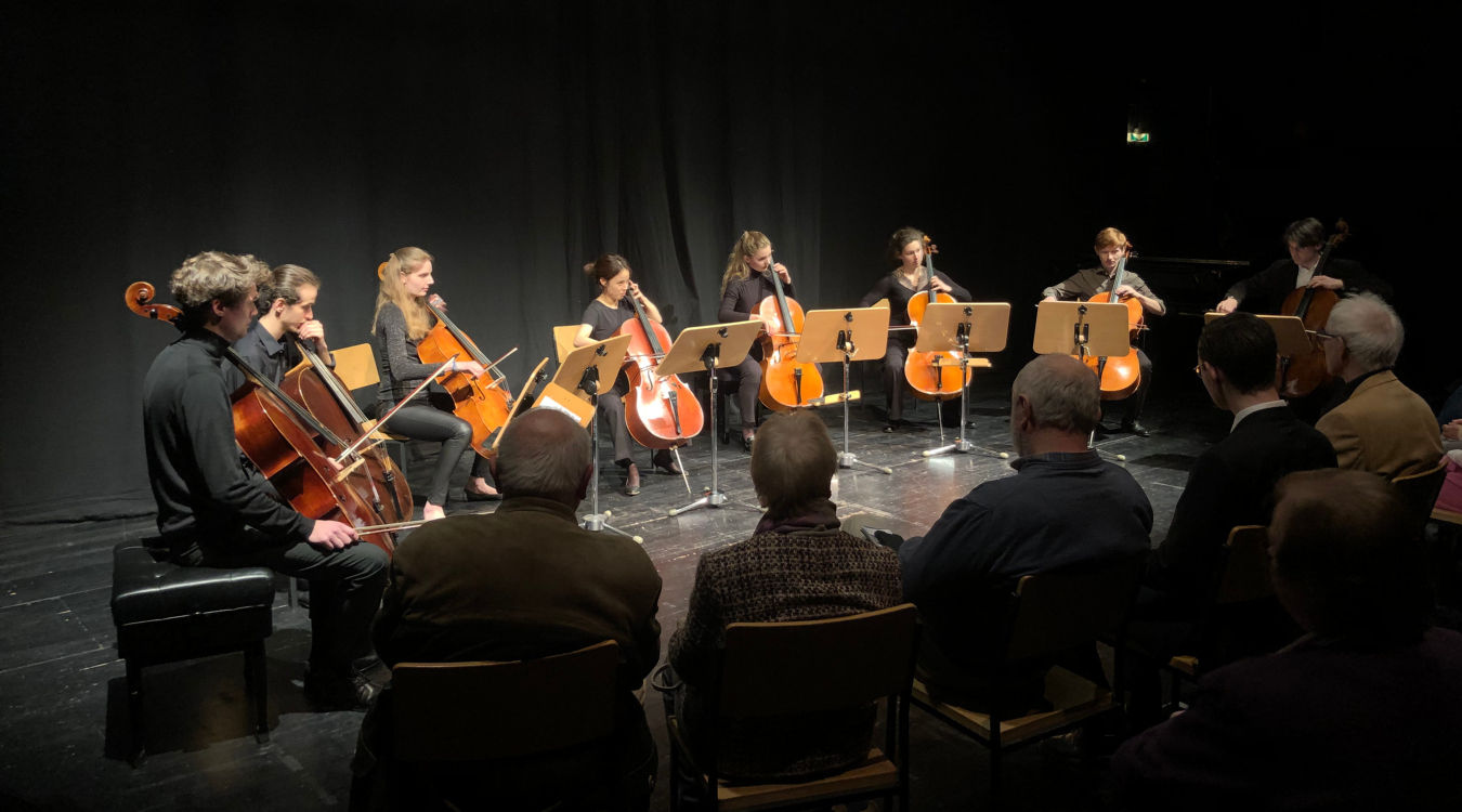 Meisterkurs für Violoncello von Prof. Jakob Spahn Mehrere Cellisten sitzen nebeneinander und spielen vor einem Publikum.