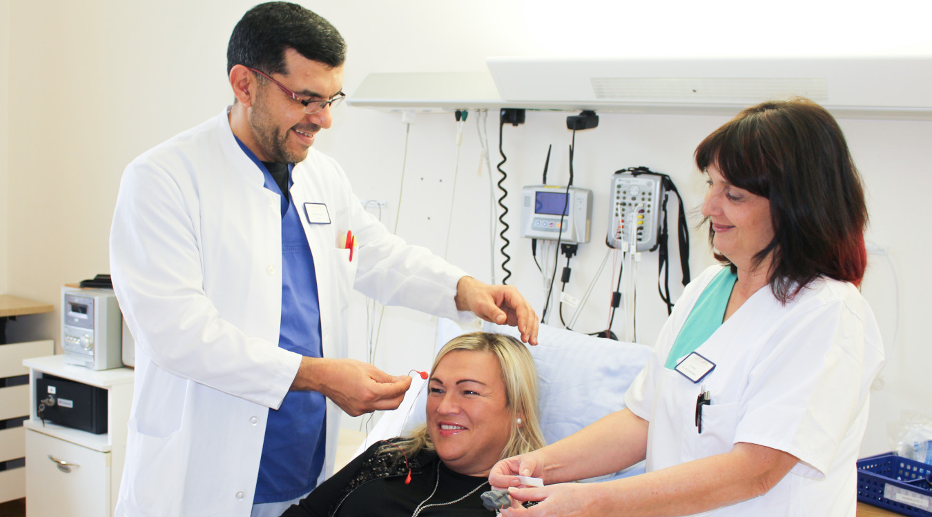 Hilfe bei Atemaussetzern in der Nacht Ein Arzt mit weißem Kittel und eine Krankenschwester behandeln eine Patientin.