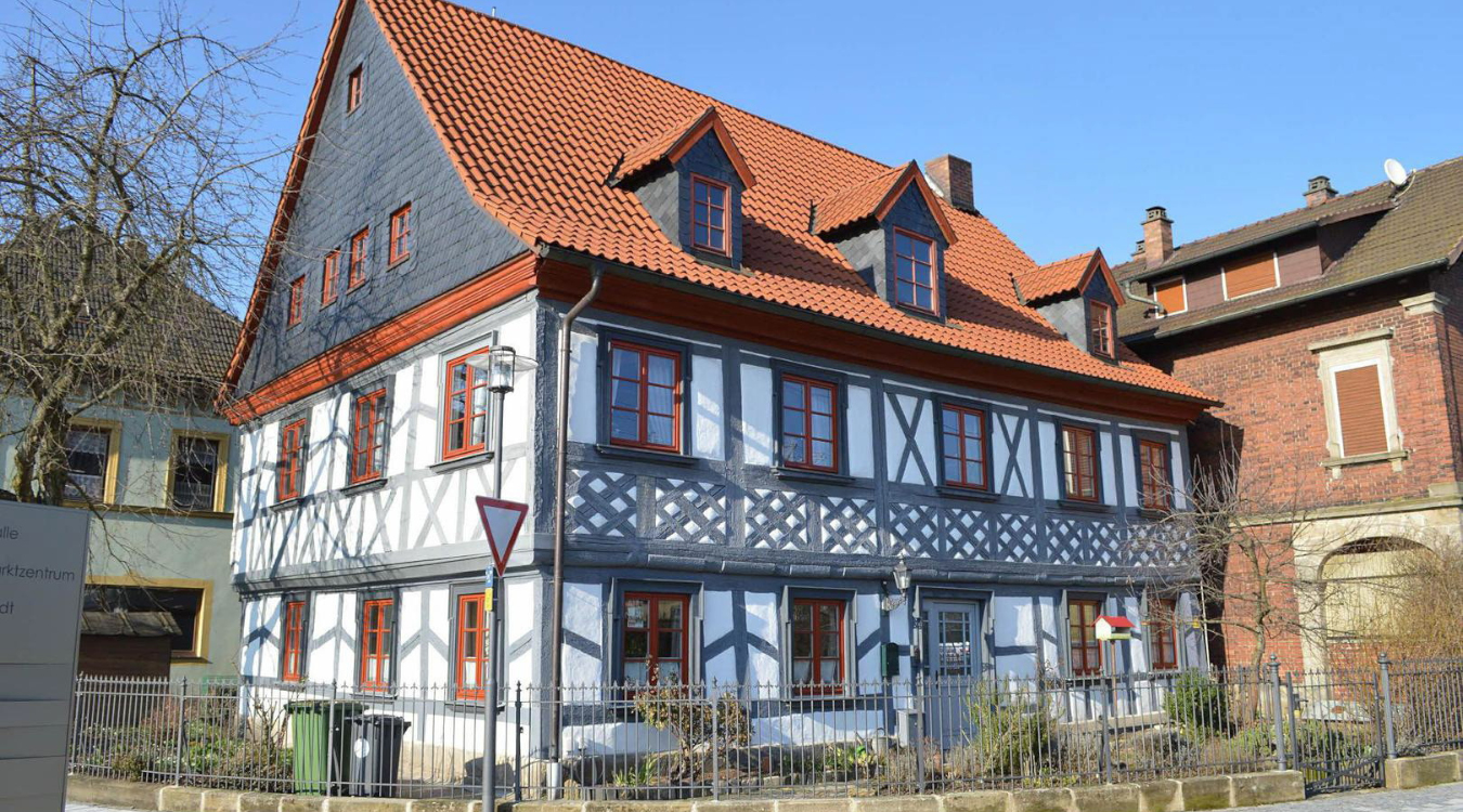 Ein weiß-graues Fachwerkhaus mit roten Ziegeln und Fenstern.