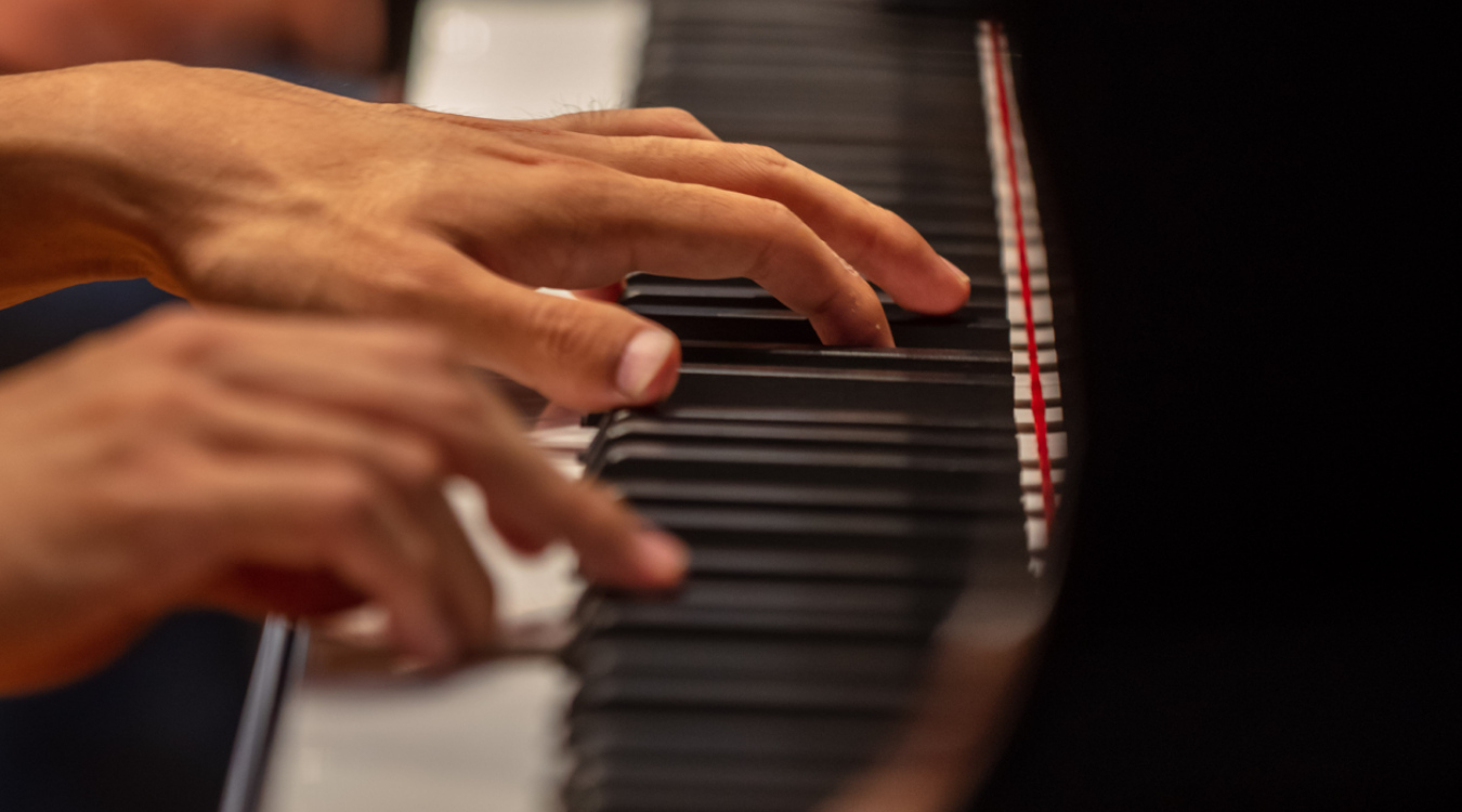 Zwei Männerhände spielen auf einem Klavier