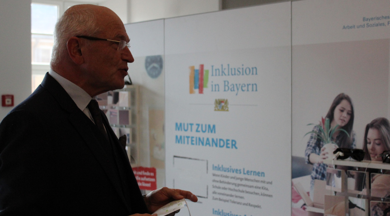 Das Bild zeigt den Bezirkstagspräsidenten Dr. Günther Denzler bei der Ausstellungseröffnung vor einer der Schautafeln der Ausstellung.