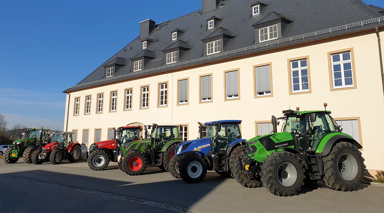 Mehrere Traktoren stehen nebeneinander vor einer Halle.