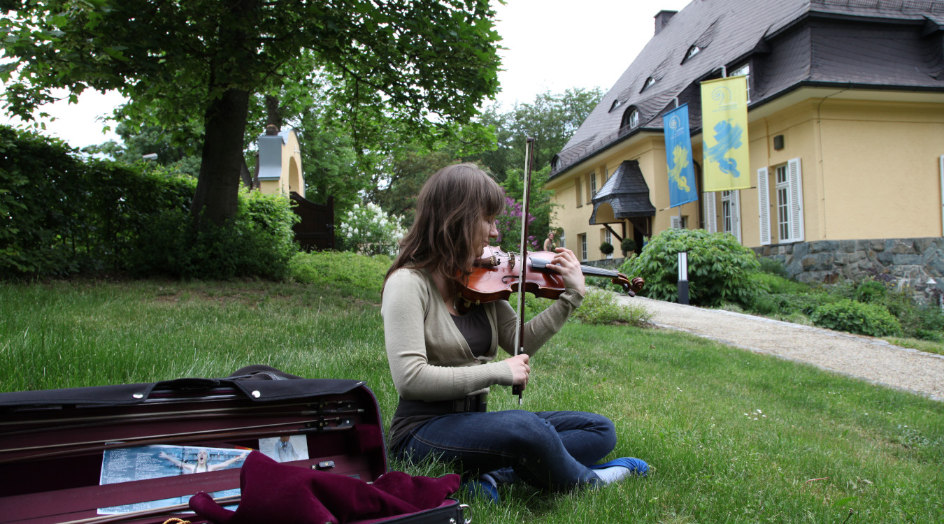 Das Bild zeigt eine junge Nachwuchsgeigerin vor der ehemaligen Künstlervilla des Violinvirtuosen Henri Marteau. 
