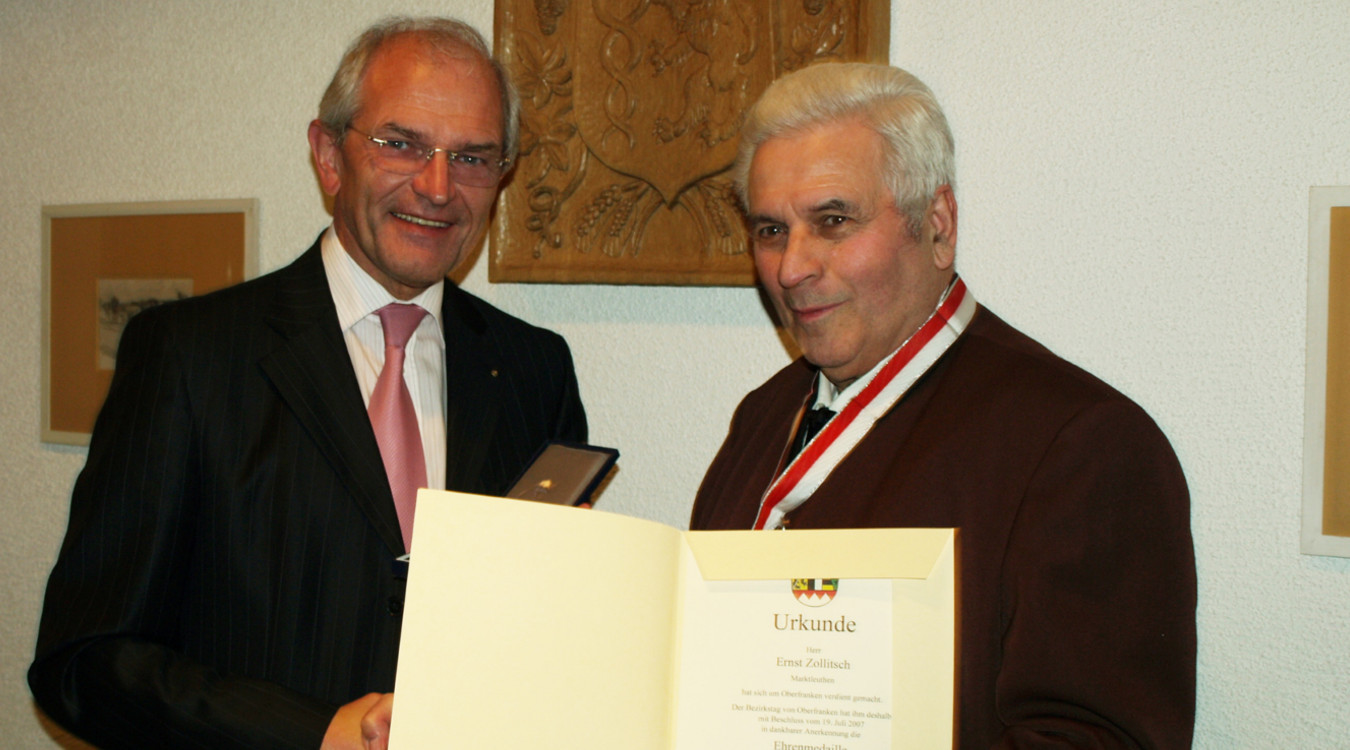 Das Bild zeigt Bezirkstagspräsident Dr. Günther Denzler und Ernst Zollitsch bei der Verleihung der Ehrenmedaille in Silber.
