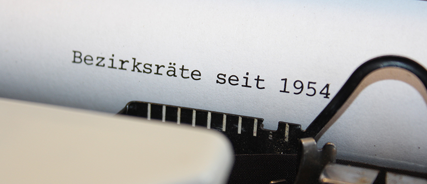 In einer Schreibmaschine ist ein Blatt eingespannt auf das "Bezirksräte seit 1954" geschrieben steht.