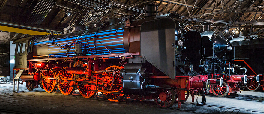 Zwei schwarze Dampflokomotiven stehen im Museum.