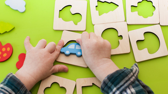 Ein Kind ordnet Formen in einem Holzpuzzle zu